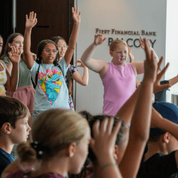 Campers raising their arms in a large group activity